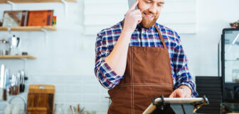 Bearded man holds phone as he looks at POS v3 ScaleMaxWidthWzEwMjRd